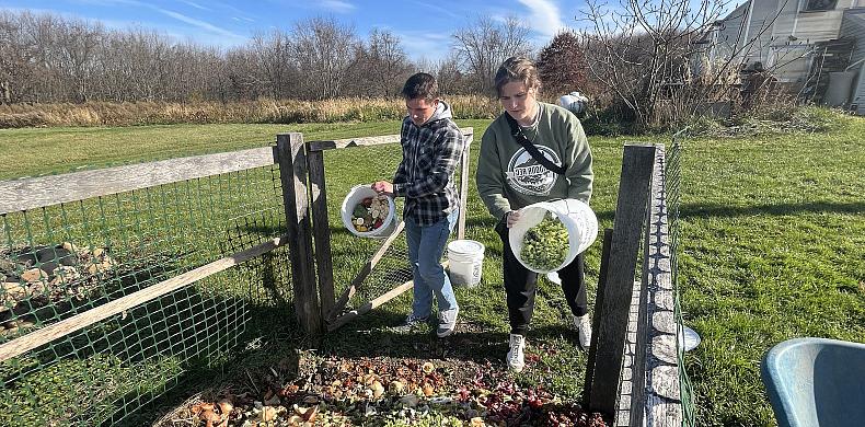 Sarah Joy '26 and Patrick Cross '24 toss pre-consumer food waste into the composting bin at Susquehanna's 花园校区.